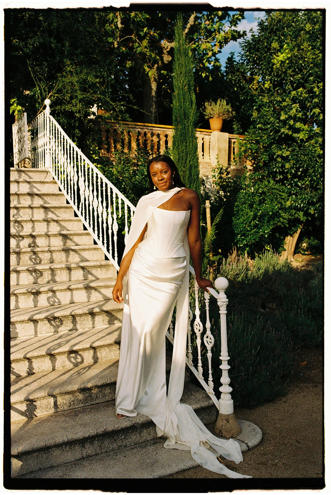 Editorial bridal portrait on white stone stairs in a Mediterranean garden, analog film aesthetic by Jessica North photography.