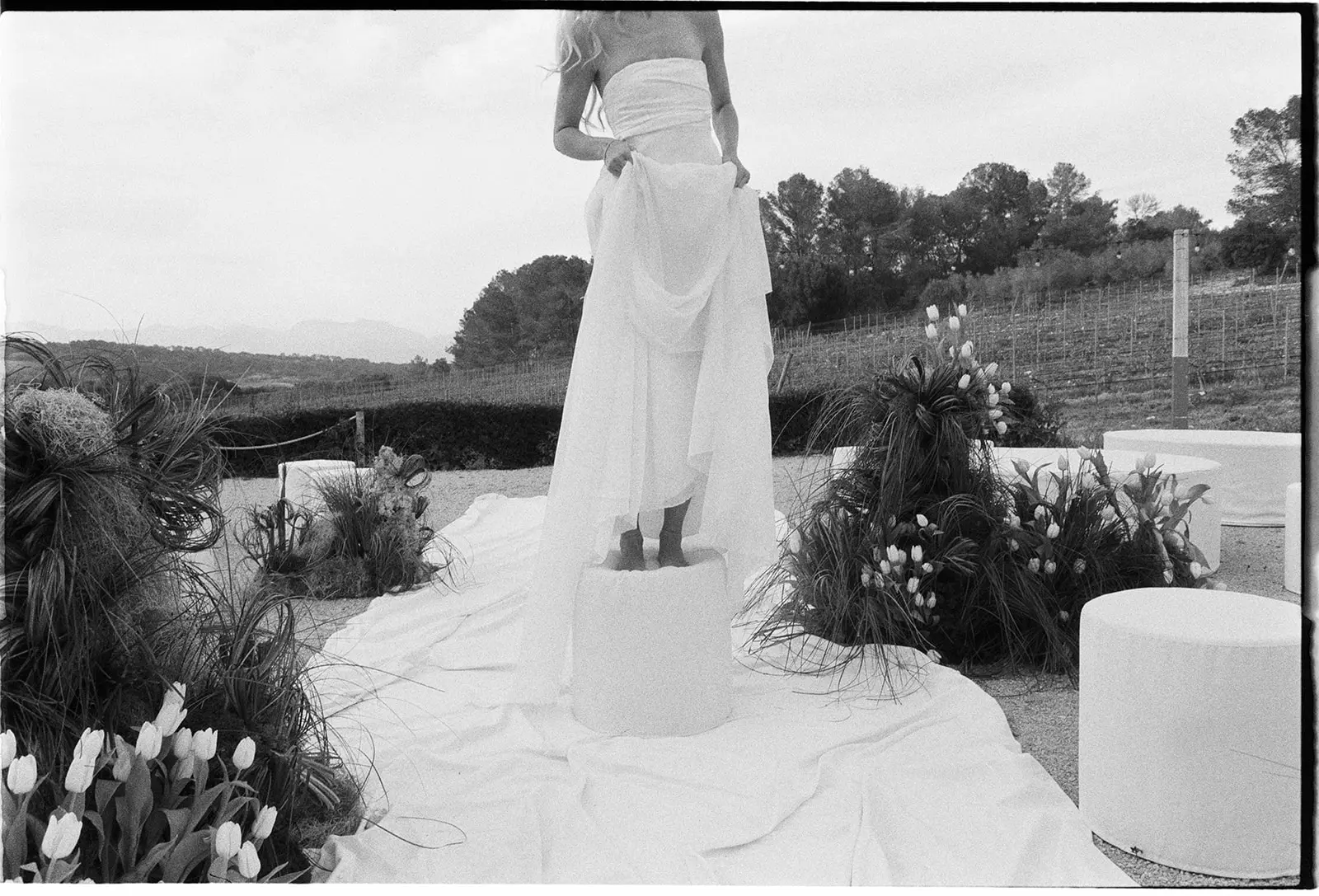 Editorial black and white wedding photography of a bride standing on a pedestal surrounded by artistic tulip installations by Jessica North.