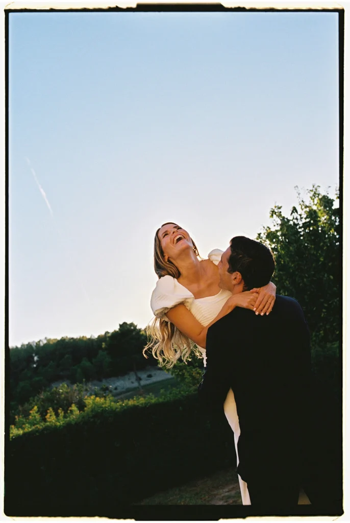 Unposed groom lifting laughing bride at Biniorella, Mallorca. analog film wedding portrait by Jessica North