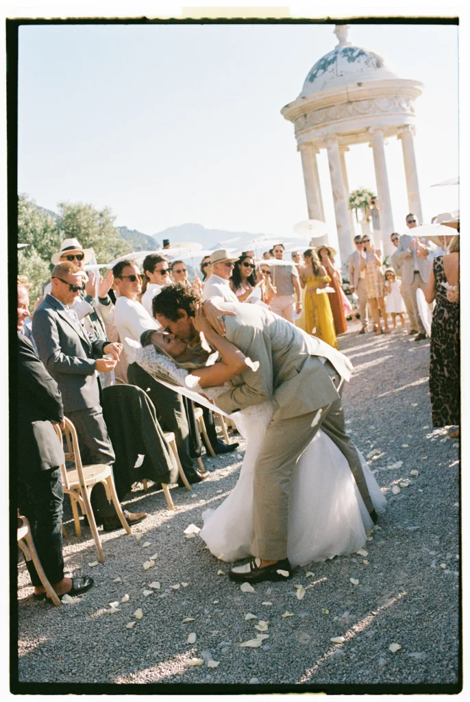A couple sharing a passionate kiss while walking down the aisle after their ceremony exit at Son Marroig, captured on 35mm film.